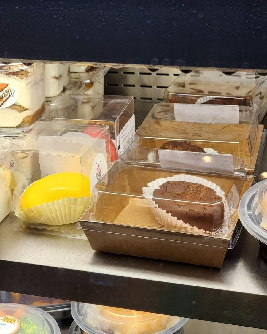 A shelf in Bizinka's display case with tiramisu cups and dome-topped cakes