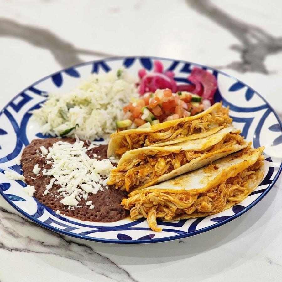 Shredded chicken tacos with rice, beans and pico de gallo on a hand-painted plate